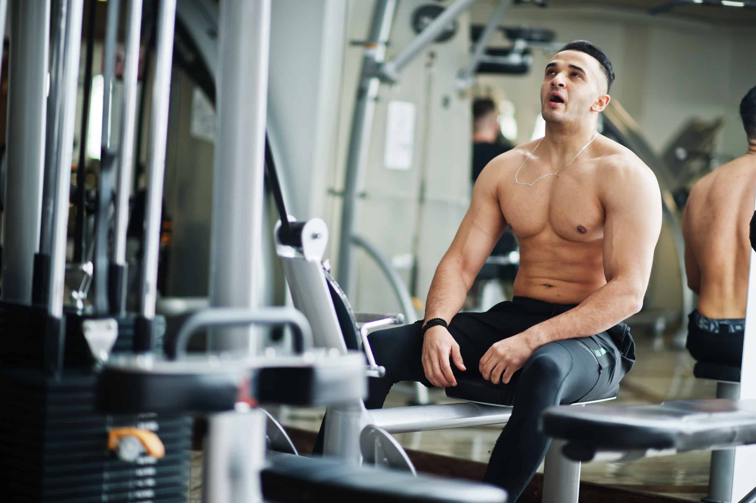 bare-chested man in gym on bench press before working out